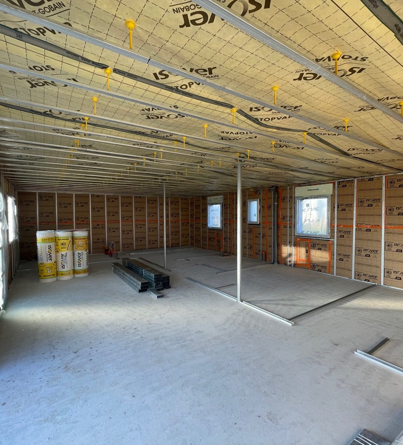 Intérieur d'une maison neuve en construction, isolation de la toiture avec membrane d'étanchéité pare vapeur et murs en laine de verre